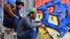 Migrants sit in front of an abandoned building in the northwestern Bosnian town of Velika Kladusa in May.