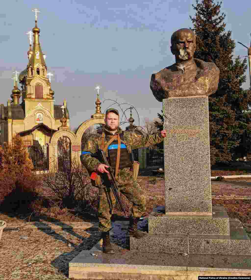 A Ukrainian soldier poses next to the Shevchenko monument in March 2022.&nbsp;