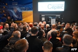 Ukrainians gather in front of a closed Ukrainian passport service point at a shopping center in Warsaw on April 24.