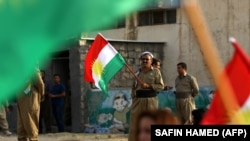 A Peshmerga member affiliated with the Democratic Party of Iranian Kurdistan holds a Kurdish flag ahead of the Kurdistan region's independence referendum in 2017. 