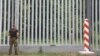 A Polish border guard patrols the area of a newly built metal wall on the border with Belarus, near Kuznice, Poland, in June 2022.