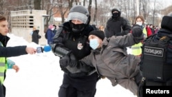 A man wearing a press vest holds a microphone as police detain a protester during a rally in support of jailed Russian opposition leader Aleksei Navalny in St. Petersburg on January 31.