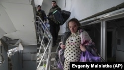 A pregnant woman flees a maternity hospital in Mariupol that was damaged in a deadly Russian bombardment on March 9. 