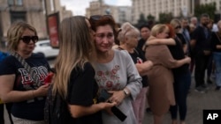 Family members and supporters comfort one another as they gather on Kyiv's Maidan on July 29 to mark the first anniversary of the attack on a prison building in Olenivka in Russian-occupied Ukraine that killed dozens of Ukrainian military prisoners. 