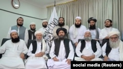 Seated with a group of men, Mullah Baradar (center of bottom row) makes a video statement from an unidentified location that was released on August 16.