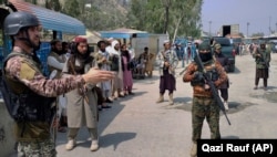 A Pakistani paramilitary soldier (left) and Afghan Taliban fighters stand guard on their respective sides, at a border crossing between Pakistan and Afghanistan at Torkham in Khyber Pakhtunkhwa Province on September 5, 2021.