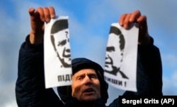 A demonstrator holds a torn portrait of then-Ukrainian President Viktor Yanukovych and shouts "Coward!" at a rally on November 29.