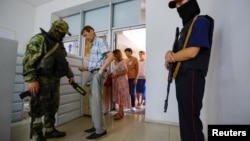 Kherson residents undergo a security check on July 25 as they visit an office to apply for Russian passports, which are now required in the Russian-controlled region to work, drive, and receive financial benefits. 