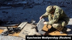 A policeman inspects fragments of a Russian-branded Shahed-136 drone at the site of a strike on fuel storage facilities in Kharkiv on October 6.