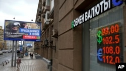 As the ruble plummets, Muscovites walk past a currency exchange office in the Russian capital alongside a billboard advertising military contracts for the country's armed forces. 