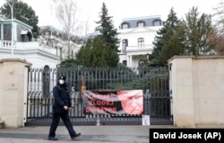 A Czech policeman outside the Russian Embassy walks past a banner attached by protesters during the diplomatic dispute in April. It shows a picture of Russian President Vladimir Putin with the words: "Killer, thief, dictator."