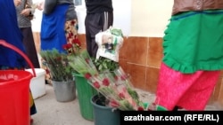 A newspaper page featuring Turkmenistan's "Protector" Gurbanguly Bedymukhammedov is used to wrap flowers.