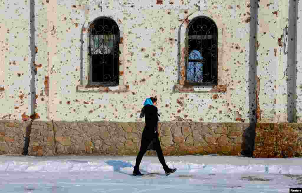 A woman walks alongside a wall of the St. Iveron Convent in Ukraine's Russian-occupied Donetsk region which has been heavily damaged by artillery and gun fire. 