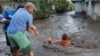 Two men work to save a resident who was swept away by floodwaters in Galati, Romania, on September 14. 