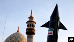 A model of a missile is carried by Iranian demonstrators as a minaret and dome of a mosque is seen in the background during an anti-Israeli rally in Tehran on April 15.