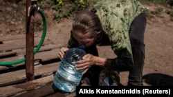 A woman drinks clean water from a jug in the eastern city of Slovyansk.