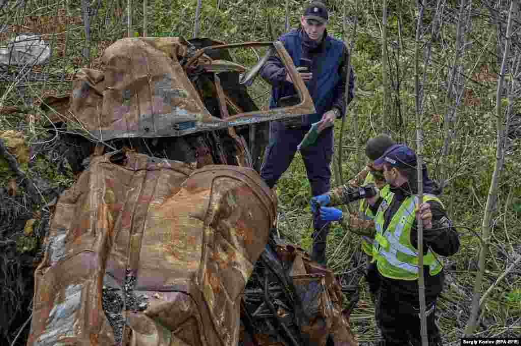 Ukrainian prosecutors and forensics experts examine a burned-out car in Izyum on October 31. According to local witnesses, three people were shot dead by Russian troops in or near this car during the occupation. &nbsp;