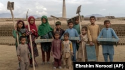 Afghan children pose for a photo at the brick factory where they work on the outskirts of Kabul. There are at least 1 million child laborers in Afghanistan, where incomes have plummeted and millions are on the brink of starvation.