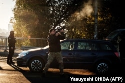 A policeman fires his rifle at an incoming kamikaze drone in central Kyiv on October 17.