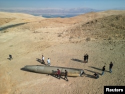 People stand around the remains of an Iranian ballistic missile after strikes on Israel near the southern city of Arad on October 2.