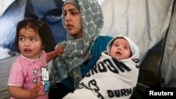 A Syrian refugee woman holds her 40-day-old son as a girl stands with them at a makeshift camp for refugees and migrants at the Greek-Macedonian border near the village of Idomeni, Greece. Syrian refugees are banned from entering the United States indefinitely under an executive order signed by U.S. President Donald Trump. (file photo)