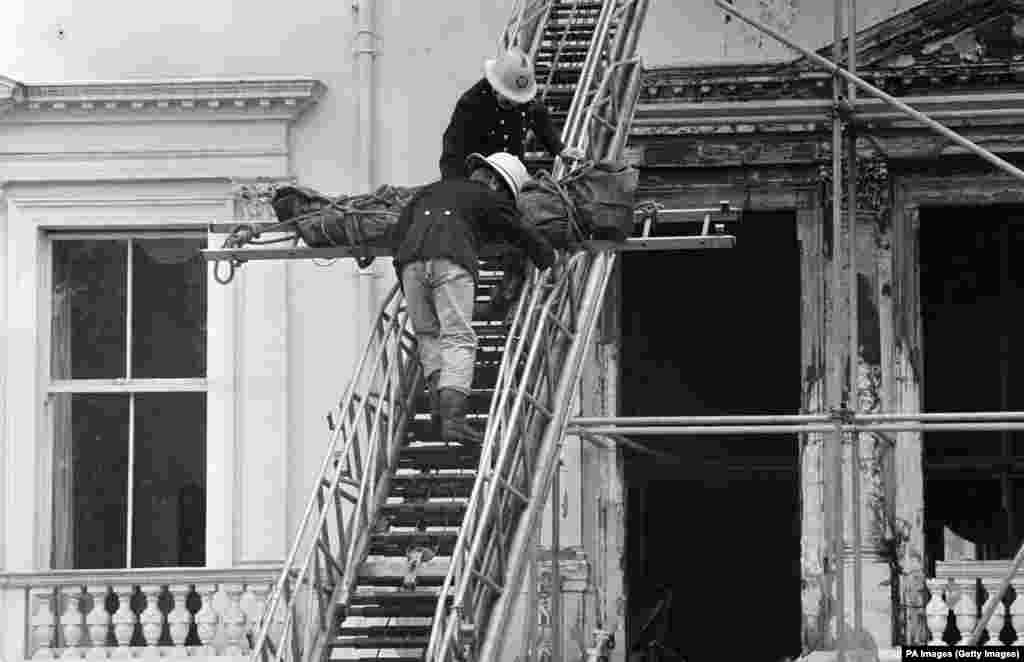 Firefighters remove one of the bodies found in the charred remains of the embassy on May 7, 1980. The corpse, wrapped in a dark green body bag, was lowered from a second-floor front window.