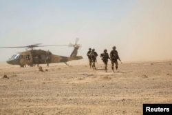 Afghan National Army troops disembark from an Afghan Air Force Black Hawk helicopter during a troop resupply at Camp Shorabak in Helmand Province in July 2018.