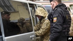 A Ukrainian sailor (left) is escorted by a Russian police officer from a court in Simferopol, Crimea, on November 28.