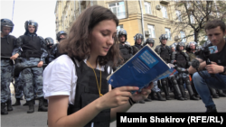 An activist reads the Russian Constitution out loud while surrounded by Russian riot police in Moscow on July 27.