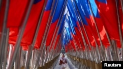 <p>A woman walks amid a display of Russian state flags installed on a square in central Moscow on February 24, the third anniversary of Russia's full-scale invasion of Ukraine. 