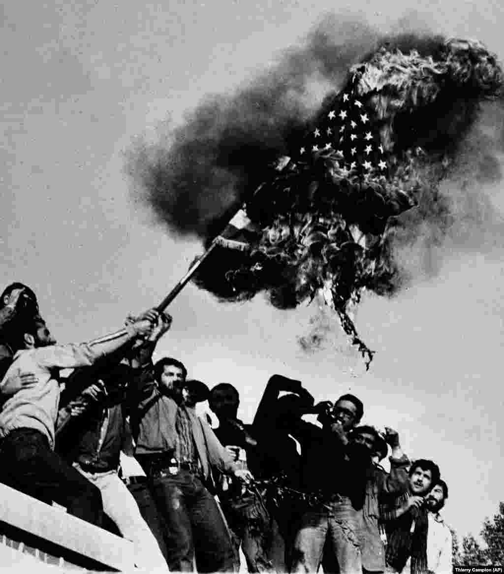 Demonstrators burn an American flag on November 9, 1979, atop the wall of the U.S. Embassy in Tehran. Weeks after the shah&#39;s departure, Ayatollah Ruhollah Khomeini returned from his 14-year exile in Paris to jubilant crowds. In March 1979, a referendum showed an overwhelming margin in favor of replacing the monarchy with an Islamic government.