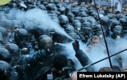 On November 24, the first clashes took place in front of the Ukrainian government building in Kyiv. In this image, protesters and riot police spray tear gas at each other.