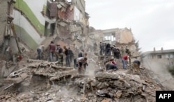 Rescue workers and local residents remove debris of an apartment building hit by a missile during an air strike in the eastern Ukrainian town of Snizhne on July 15, 2014.