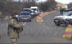 A Ukrainian soldier stops cars at a a checkpoint in Mayorsk, in the Donetsk region, on March 16.