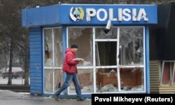 A man walks past a police station in Almaty that was vandalized during mass protests triggered by a fuel price increase.