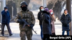 A Kazakh soldier patrols a street as relatives of the arrested in the anti-government protests gather near a police station in Almaty.