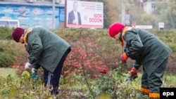 Two Moldovan women work against the backdrop of an electoral campaign poster for presidential front-runner Igor Dodon in Chisinau on October 27. 