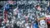 People hold up lights, Slovak and EU flags as they take part in an antigovernment protest at Bratislava's Freedom Square, February 7, 2025. 