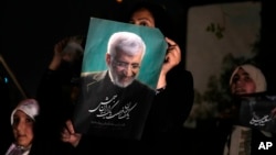 Saeed Jalili's supporters hold up one of his campaign posters ahead of Iran's presidential election on June 28. Jalili finished second among four candidates and will head to a run-off vote on July 5. 