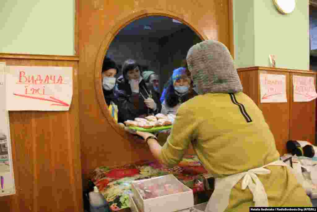 Volunteers line up to take food and drinks on trays to distribution points on Independence Square.