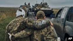  A Ukrainian soldier helps a wounded member of his unit on the road in Ukraine's Kharkiv region in 2022.