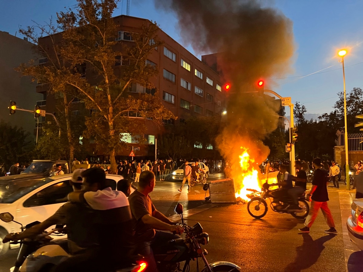 A police motorcycle and a trash bin burn during a protest over the death of Mahsa Amini.