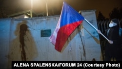 A protester holds a Czech national flag in front of the walls of the Russian Embassy in Prague on April 18. Protesters splashed ketchup on the walls of the embassy to call attention to the deaths of the two people in a 2014 arms depot explosion the Czechs now blame on Russian agents.