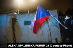 A protester holds a Czech national flag in front of the walls of the Russian Embassy in Prague. Protesters splashed ketchup on the walls of the embassy to call attention to the deaths of the two people in the 2014 explosion.