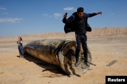 A man jumps off the apparent remains of a ballistic missile lying in the desert, following an attack by Iran on Israel, near the southern city of Arad, Israel, on October 2.