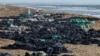 Volunteers work to clear spilled oil on the coastline following an incident involving two tankers damaged in a storm in the Kerch Strait on December 21.