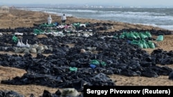 Volunteers work to clear spilled oil on the coastline following an incident involving two tankers damaged in a storm in the Kerch Strait on December 21.