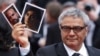 Director Mohammad Rasoulof holds pictures of cast members Missagh Zareh (left) and Soheila Golestani following the screening of his film The Seed Of The Sacred Fig in Cannes. 