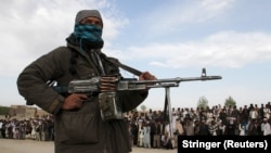 A Taliban militant and locals attend the execution of three men condemned by a shadow court in Ghazni Province. (file photo)