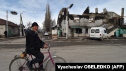 An elderly man cycles past a burnt-out building in the majority-Dungan village of Masanchi in southern Kazakhstan's Zhambyl region, close to the border with Kyrgyzstan, on February 12.